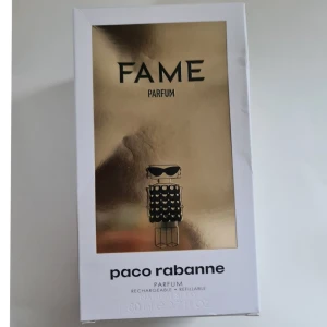 Fame Parfum från Paco Rabanne - Unik parfymflaska från Paco Rabanne i form av en stiliserad figur med solglasögon. Flaskan är guld- och svartfärgad med ett mönster som liknar paljetter. Parfymen är påfyllningsbar och kommer i en elegant förpackning.