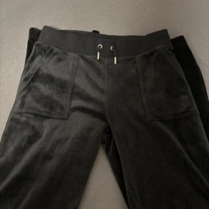 Svarta mjukisbyxor från Juicy Couture - Snygga svarta mjukisbyxor från Juicy Couture i mjukt material. Byxorna har en bekväm resårmidja med snörning och praktiska fickor både fram och bak. Perfekta för en avslappnad stil.