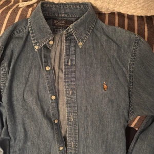 Jeansskjorta från Polo Ralph Lauren - Snygg jeansskjorta från Polo Ralph Lauren i slim fit. Skjortan har knappar framtill och en broderad logotyp på bröstet. Perfekt för en stilren look.