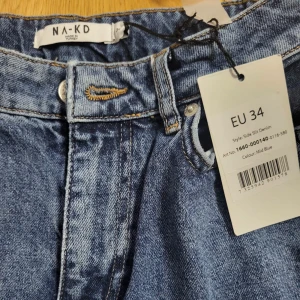Blå jeans från NA-KD - Snygga blå jeans från NA-KD i modellen 'Side Slit Denim'. De har en klassisk femficksdesign och en stilren look. Perfekta för en avslappnad stil.