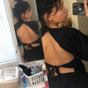 Svart topp med öppen rygg och knyt - Snygg svart topp med öppen rygg och knytband. Perfekt för en kväll.