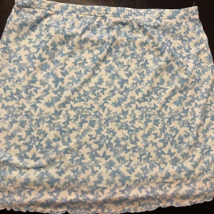 Blå och vit kjol från Shein - Säljer en söt blå och vit kjol från Shein med ett fint blommönster. Kjolen har en elastisk midja för en bekväm passform. Perfekt för en avslappnad stil.