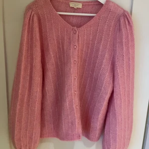 Rosa kofta från Sézane - Säljer en superfin rosa kofta från Sézane i storlek XL. Den är stickad med en mjuk blandning av mohair och merinoull, vilket gör den både varm och bekväm. Koftan har långa ärmar och knappar framtill. Perfekt för kyliga dagar! 🌸 aldrig använd. Köpt april 2023! Nypris: 115€