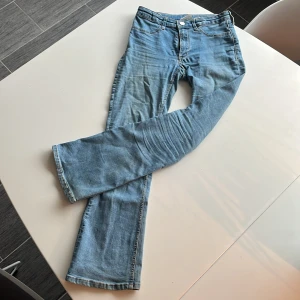 Blå jeans från H&M - Säljer ett par snygga blå jeans från H&M i storlek 152. De har en flared leg och justerbar midja, vilket gör dem superbekväma. Perfekta för vardagsbruk med en låg midja som ger en avslappnad look. 