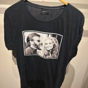 Svart t-shirt med tryck från Limitato - Säljer en svart t-shirt från Limitato med ett coolt tryck av två personer på framsidan. T-shirten är i normal passform och har korta ärmar. Perfekt för en avslappnad stil eller en utekväll. 