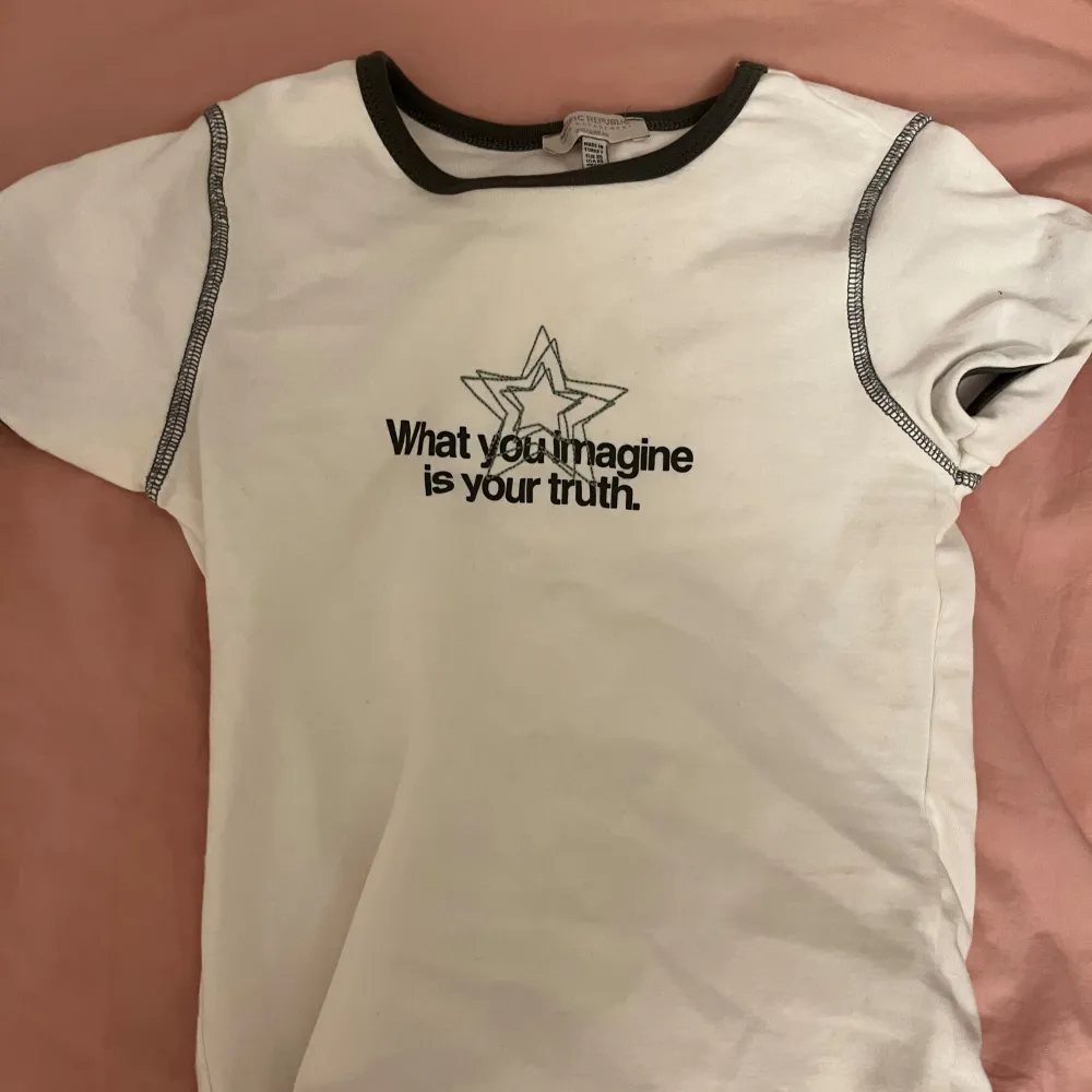 Säljer en vit t-shirt med svart text och stjärna på bröstet: 'What you imagine is your truth'. Den har svarta kontrastsömmar och en rund halsringning. Kommer dock inte till andvändning längre så därför säljs den!. T-shirts.