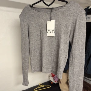 Grå tunn långärmad tröja från Zara, Strl M - Grå långärmad tröja från Zara. Den är gjord av en mjuk blandning av viskos, polyester och polyamid,det kommer med axelvaddar.nya med prislapp 