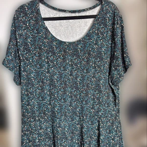 Blommig tröja i grönt och svart - Tröja med blommigt mönster i grönt och svart storlek 2XL. Den har en rund hals och lite längre korta ärmar. Materialet känns mjukt och bekvämt. 