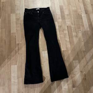 Säljer ett par snygga svarta bootcut jeans i mycket bra skick. De har en klassisk femficksdesign med knappar och dragkedja framtill. 