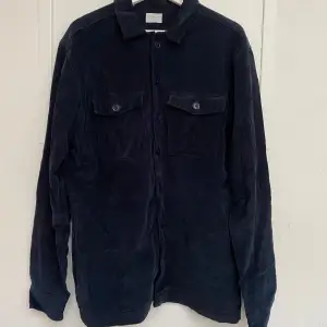 Säljer en snygg mörkblå overshirt från Selected Homme i manchester. Den har långa ärmar och två bröstfickor med knappar. Perfekt för höst och vår när du vill ha en stilren look. Regular fit och riktigt skön att ha på sig. Passar både till vardags och lite finare tillfällen. Skick: Använt (skavda armbågar, se bild) - Artnr:C043