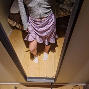 Blommig omlottkjol från Vero Moda - Säljer en superfin blommig omlottkjol från Vero Moda i storlek S. Kjolen har ett härligt mönster i lila, rosa och grönt med volangdetaljer längst ner. Perfekt för vår och sommar! 💐