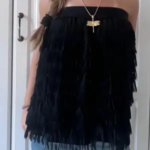 Säljer en superfin svart axelbandslös topp med fransar som ger en härlig boho-känsla. Perfekt för en utekväll eller fest! Toppen är i bra skick och har en bekväm passform. Den är både stilren och trendig, och passar perfekt till jeans eller kjol.