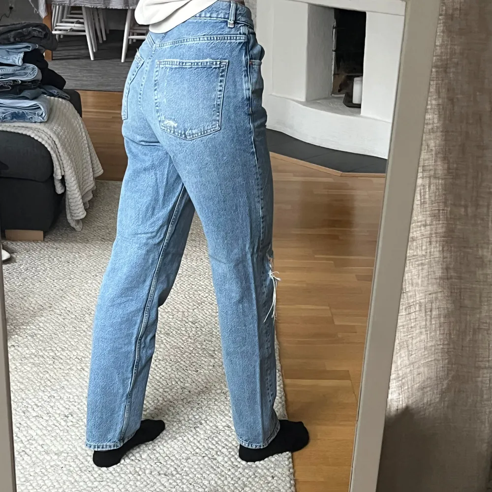 Säljer ett par snygga blå jeans med slitningar på knäna. De är högmidjade och har en straight passform som ger en avslappnad look. Köpta på gina och är utan skavanker . Jeans & Byxor.