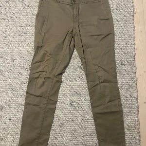Beige chinos från These Glory Days - Säljer ett par snygga beige chinos från These Glory Days i storlek 50. De har en klassisk design med knappar och dragkedja framtill. Perfekta för både vardag och fest! 🕺