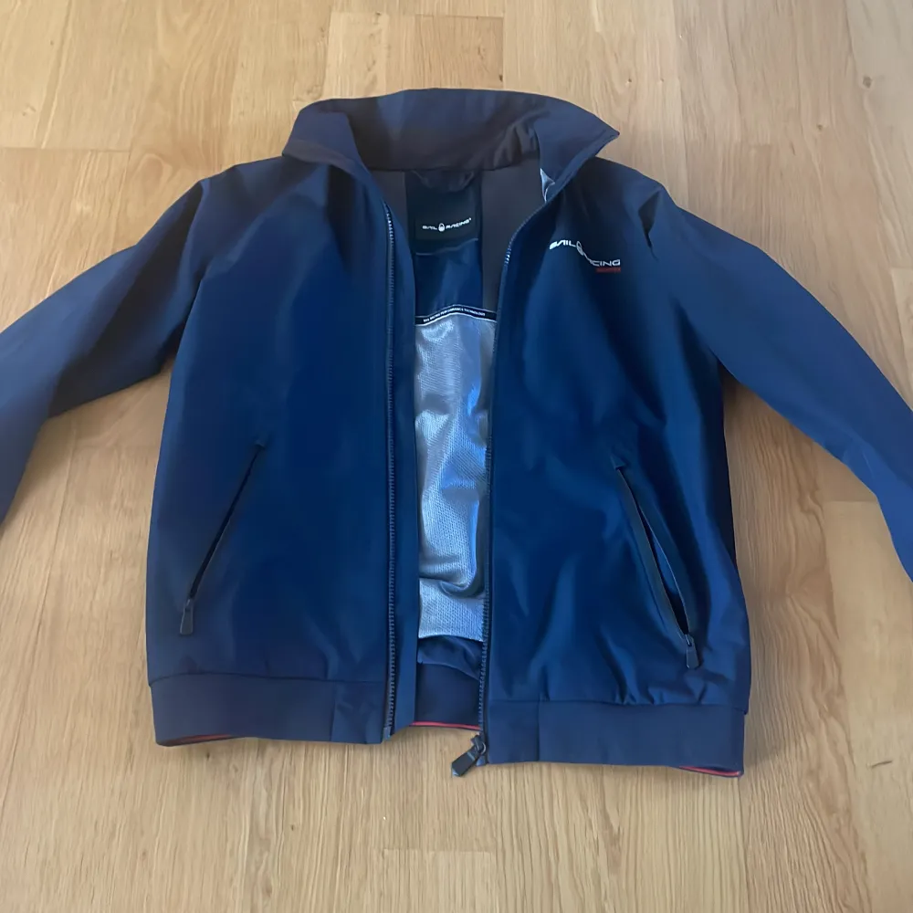 Säljer en blå Gore-Tex jacka från Sail Racing i mycket bra skick. Jackan har en dragkedja framtill och är långärmad. Perfekt för höst och vår med sitt vattentäta material. Den har en stilren design med broderad logga på bröstet. Passar både till vardags och utomhusaktiviteter.. Jackor.