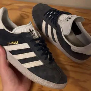 Säljer dessa snygga Adidas Gazelle-skor i mörkblå färg. Storlek 42. Skicket är 7/10, inga defekter, bara normala tecken på användning. Nypriset ligger runt 1000 kr, mitt pris är 499 kr. Kontakta mig gärna privat för fler frågor. Priset kan diskuteras