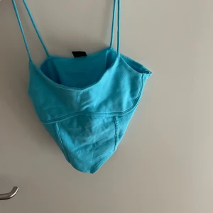 Turkos linnetopp - Säljer en snygg turkos linnetopp med smala axelband. Perfekt för sommardagar eller en festlig kväll. Toppen har en enkel och stilren design.