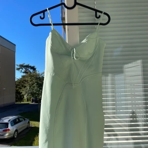 Mintgrön klänning med snörning - Säljer en superfin mintgrön klänning med smala axelband och en snygg snörning framtill. Klänningen är tight och kort, perfekt för sommarens fester eller en utekväll. Materialet känns mjukt och bekvämt mot huden.
