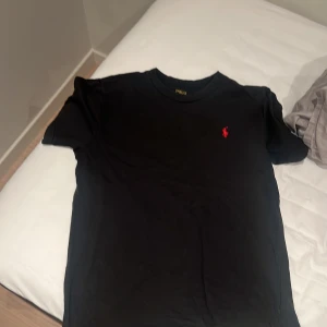 Svart polo t shirt - Skick 6/10 man ser att den tidigare är använd. Denna passar på 10-12 åringar. Äkta såklart