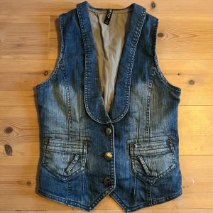 Vintage jeans väst - Snygg jeans väst i 70-talsstil och i gott skick med spänne i ryggen och två små fickor framtill. 