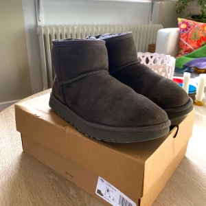 UGGs - Gråbruna UGGs classic mini.  Innersidans söm på den vänstra skon har lagats men har hållt bra(se bild) därav priset.   UGGs kartongen dom kommer skickas i är inte från de här paret. Såklart äkta