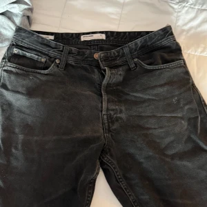 Svarta jeansbyxor från Jack & Jones - Snygga svarta jeansbyxor från Jack & Jones med klassisk femficksdesign och knappgylf. Perfekta för en stilren look. Passar bra till både vardag och mer uppklädda tillfällen.