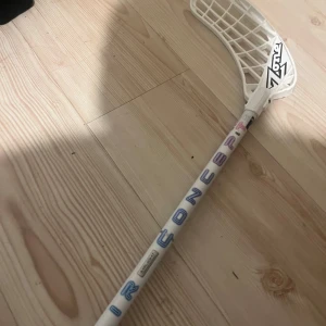 Innebandyklubbor från Zone - Säljer flera innebandyklubbor från Zone i olika färger och modeller. En vit med blå text, en svart med AIRLIGHT text, och en rosa med vit text. Perfekt för innebandyentusiaster som vill ha variation i spelet. Klubborna har olika blad och grepp för bästa spelupplevelse.