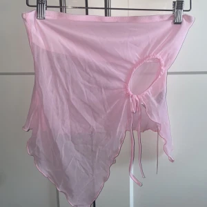 Rosa tubtopp med knytning - Säljer en söt rosa tubtopp med knytning framtill. Toppen har en asymmetrisk nederkant och är perfekt för varma dagar. Den är tillverkad i ett lätt och luftigt material. Aldrig använd & lappen sitter kvar!