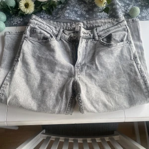 Grå H&M jeans - Snygga grå jeansbyxor med klassisk femficksdesign och knappgylf. Perfekta för en avslappnad stil. De har en rak passform och är tillverkade i ett slitstarkt material.