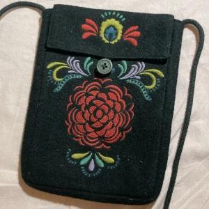 Svart broderad axelväska - Charmig svart axelväska med färgglatt broderi i rött, gult, blått och grönt. 