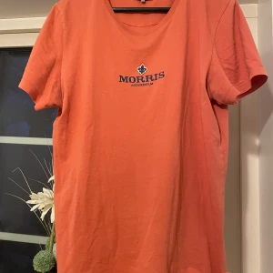 Orange t-shirt från Morris - Säljer en snygg orange t-shirt från Morris med korta ärmar och ett broderat emblem på bröstet. Perfekt för en avslappnad stil med en touch av elegans. Storlek M. Vet ej om den än äkta köpt av nån på vinted.