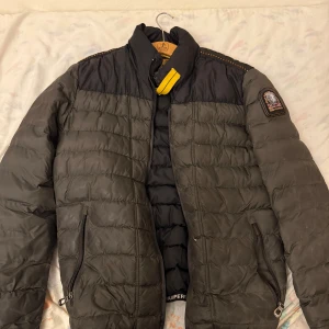 Svart quiltad jacka från Parajumpers - Säljer en snygg svart quiltad jacka från Parajumpers med broderad logga på ärmen. Jackan har en dragkedja framtill och är perfekt för kyligare väder. Den har långa ärmar och en stilren design.