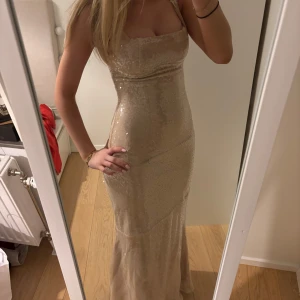 Champagnefärgad paljettklänning - Säljer en jättefin champagnefärgad balklänning med paljetter. Klänningen har en figursydd passform och sitter så fint på. Från babyboo. Passar XS/S. Inte använd endast testad, lappen sitter kvar.  Bra pris med tanke på att frakt och tull har betalats. Skriv för fler bilder!