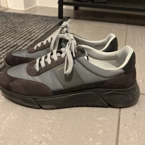 Axel arigato skor - Snygga grå sneakers från Axel Arigato med mörkare grå mockadetaljer och snörning. Skorna har en robust svart sula och är perfekta för en stilren look.Skick 9/10 passar mer 45