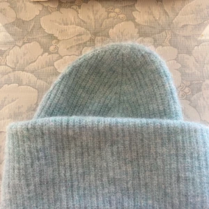 Ljusblå stickad mössa från ARKET - Säljer min mysiga ljusblåa stickade mössa från arket som jag köpte förra vintern, använder den tyvärr inte mycket alls så därför säljer jag den🥰 skriv gärna för mer bilder!