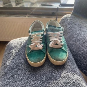 Saint Laurent sneakers i mocka - Snygga turkosa Saint Laurent sneakers i mocka med vita snören och en krämfärgad sula. Perfekta för en avslappnad stil och ger en färgklick till din outfit.