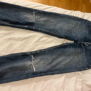 Utsvängda Lee jeans - Snygga blå jeans från Lee med slitna detaljer och en klassisk femficksdesign. Jeansen har en utsväng passform är midwaist. Jeansen är lite slitna vid hällarna därav priset 🥹