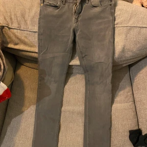 Grå jeansbyxor från Replay - Snygga grå jeansbyxor från Replay med en klassisk femficksdesign. De har en smal passform och är perfekta för en stilren look. Storlek 28:30