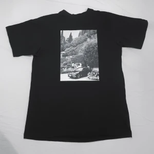 Svart t-shirt med biltryck - Snygg svart t-shirt med ett coolt svartvitt tryck av en bil och landskap på framsidan av t-shirtren. Perfekt för en avslappnad stil.