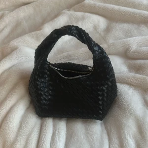 Svart flätad handväska - Snygg eftertraktad svart flätad handväska med dragkedja. Knappt använd extremt bra skick