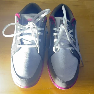 Vita och grå golfskor från Callaway - Säljer ett par vita och grå golfskor från Callaway med rosa detaljer. Skorna har snörning och en sula med dubbar för bra grepp på golfbanan. Perfekta för den stilmedvetna golfaren.