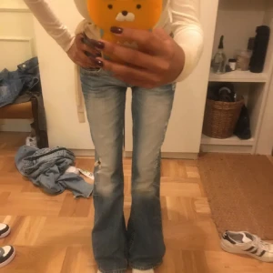 Blå bootcut jeans - Snygga blå bootcut jeans med slitningar och en klassisk femficksdesign. Perfekta för en avslappnad stil med en touch av vintagekänsla.köpta för 800kr sänkning av priset pga fickan på högersida ❤️