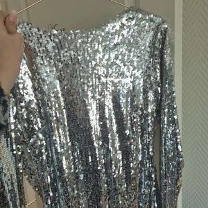 Glittrig silverklänning - Säljer en fantastisk glittrig klänning i silver med långa ärmar. Perfekt för att glänsa på festen! ✨