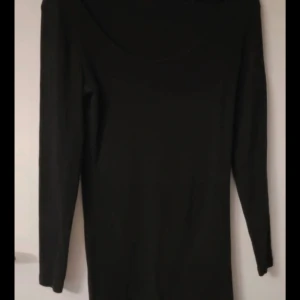 Svart långärmad klänning - Snygg svart långärmad klänning med en enkel och stilren design. Perfekt för en elegant look. Klänningen har en rund halsringning och är gjord i ett mjukt material.
