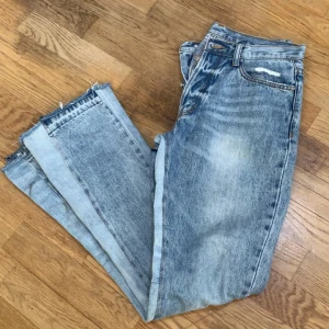Ljusa jeans från mnmi  - Snygga ljusa jeans med slitningar på framsidan och råa kanter vid bensluten. Perfekta för en avslappnad stil. De har en klassisk femficksdesign och knappgylf finns ingen skador absolut den är helt ny 