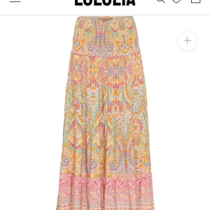 Mönstrad långkjol - Färgglad långkjol med ett livligt mönster i orange, rosa och blå nyanser. Kjolen har en elastisk midja för bekväm passform och ett bohemiskt utseende. Perfekt för en avslappnad och stilfull look till sommarn!