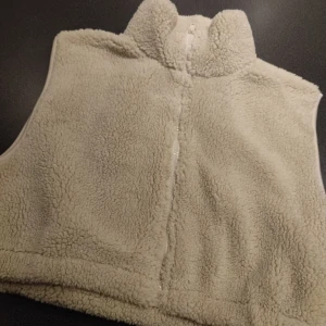 Beige fleeceväst från Only Trend - Mysig beige kort fleeceväst utan fickor från Only Trend i storlek S. Västen har en dragkedja framtill och är perfekt för kyliga dagar. Den är mjuk och bekväm att bära.