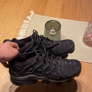 Nike vapormax plus  - Säljer ett par svarta Nike sneakers med unik sula och snörning. Skorna har en modern design med vågformade detaljer på sidan och en luftig sula för extra komfort.  Inga fel knappast använda, inga hål i bubblorna eller liknande