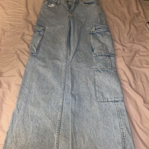 Ljusa cargobyxor från FB Sister - Snygga ljusa cargobyxor från FB Sister i jeansmaterial. Byxorna har flera praktiska fickor på sidorna och en avslappnad passform. Perfekta för en casual look med en t-shirt eller hoodie.