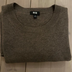 Brun kashmirtröja från Uniqlo - Säljer en mjuk och stilren brun kashmirtröja från Uniqlo. Tröjan har en rund halsringning och långa ärmar, perfekt för kyligare dagar. Passar både till vardags och mer uppklädda tillfällen. Ett måste i garderoben för den som älskar komfort och stil. Har en även ett minimalt hål på vänster axeln men som jag sjölv knappt hade märkt av.